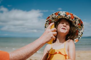 Applying sun screen to a child while on the beach on holiday