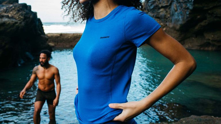 Woman wearing Finisterre Vela Bamboo T shirt with rugged coast in the background