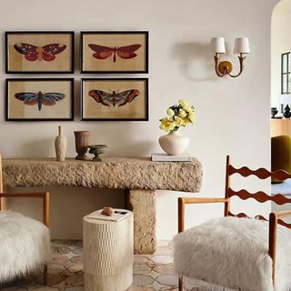 Four prints of colorful moths in gold frames in a living room