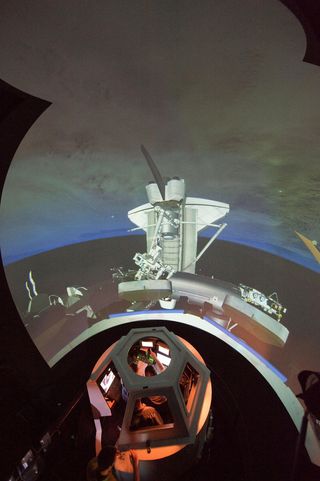 STS-133 astronauts Michael Barratt and Nicole Stott, both mission specialists, participate in an exercise in the systems engineering simulator in the Avionics Systems Laboratory at NASA's Johnson Space Center. The facility includes moving scenes of full-s