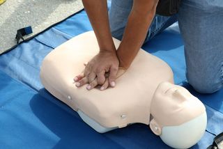 A person practices CPR on a manequin.