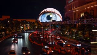 The Sphere in Vegas, displaying an eyeball, looming over the Las Vegas which has heavy traffic.