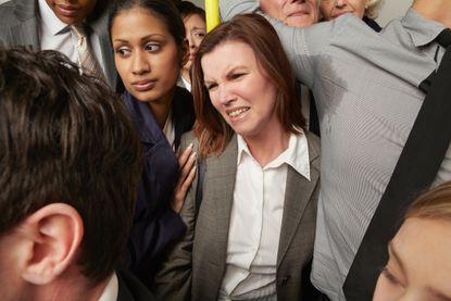 Woman and man with sweaty armpit on crowded subway train.