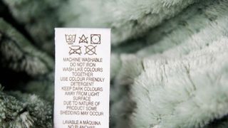 a close up picture of a fabric tag for a fleece blanket with the washing instructions on it