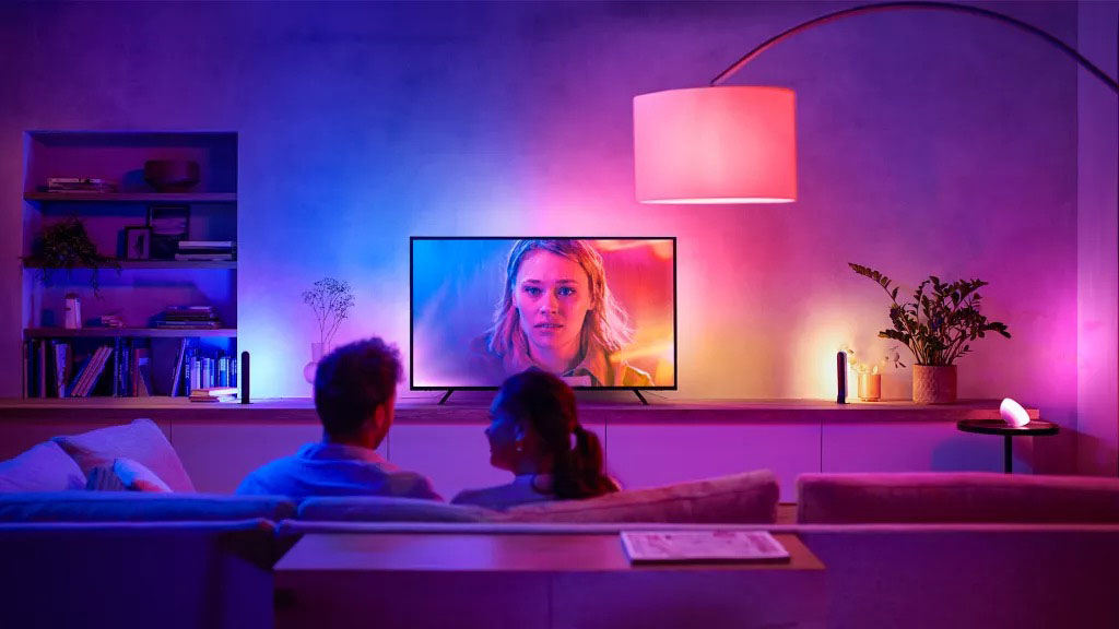 Par på sofaen foran tv'et med farverig hyggelig belysning