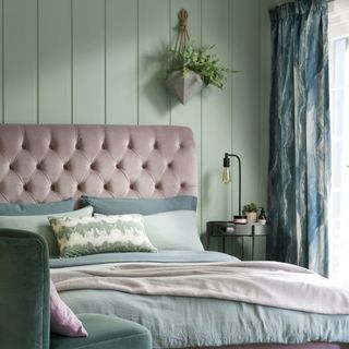bedroom with green panelled wall and pink upholstered headboard