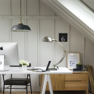 Loft study area whit white wall paneling and desk and chair