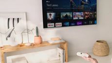 Chromecast with Google TV being used in living room with TV mounted to white wall