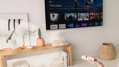 Chromecast with Google TV being used in living room with TV mounted to white wall