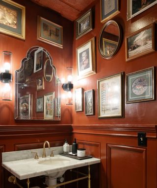 A dark orange bathroom with antique picture frames