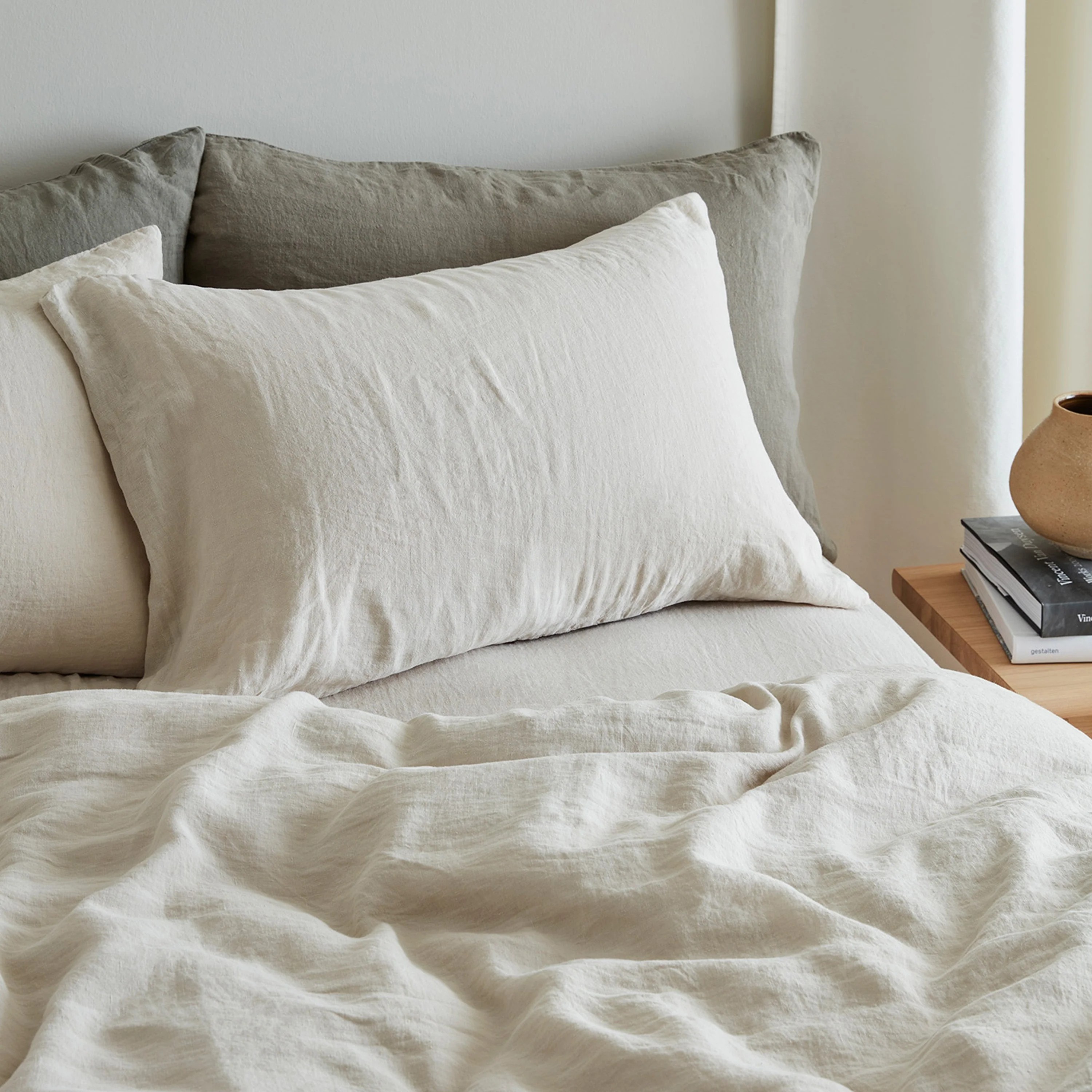 close-up image of beige and sage green linen sheets on a bed.