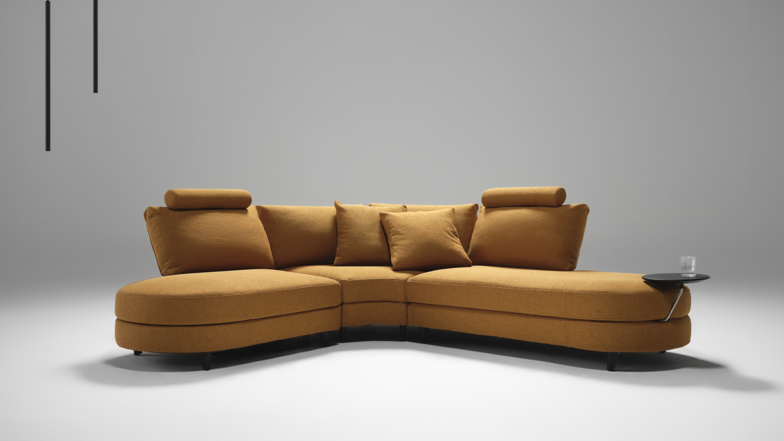 The curved King Living Delta 5 storage sofa in orange with an attached side table in a studio setting