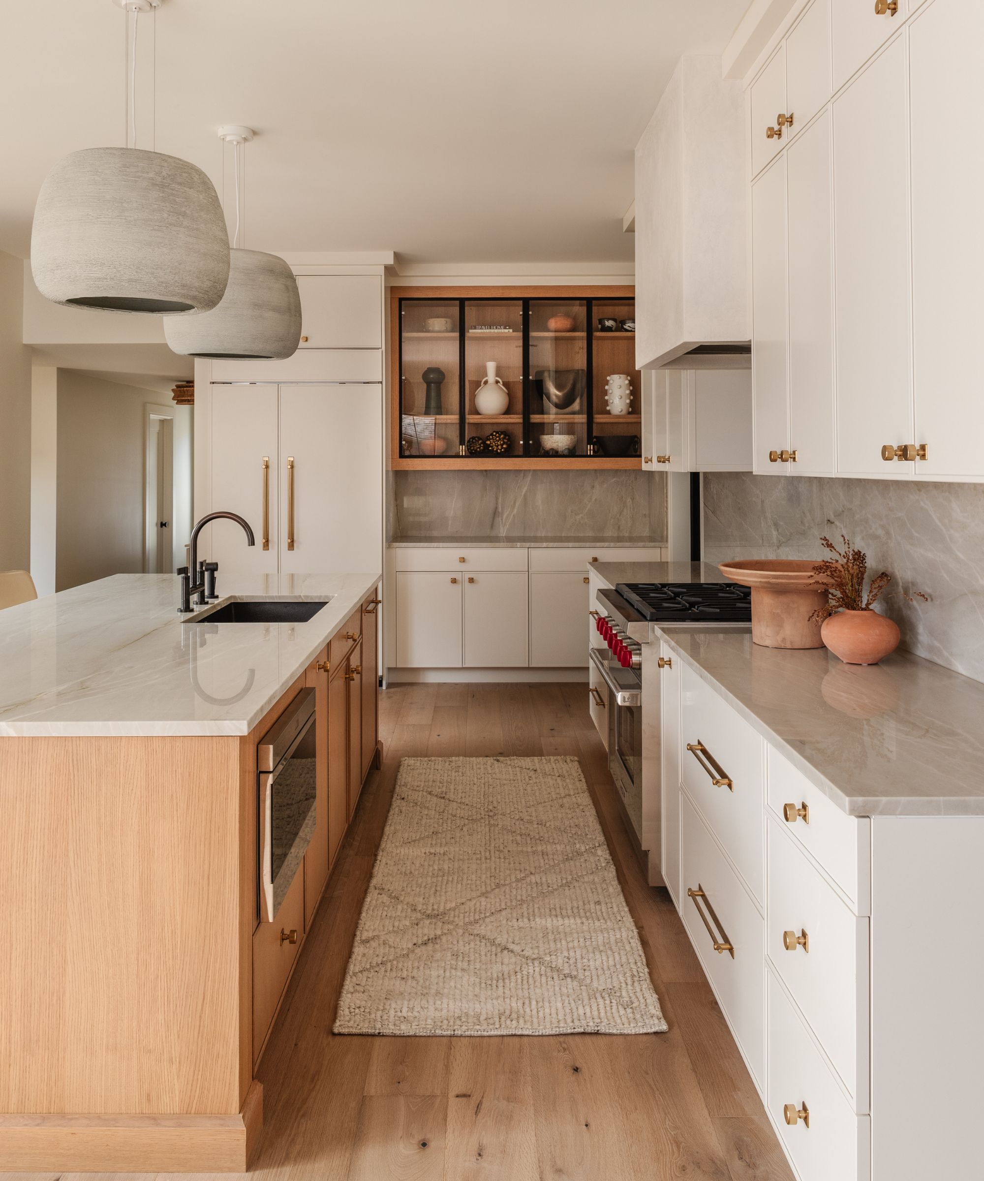 A wood and white kitchen with glass-fronted upper cabinets