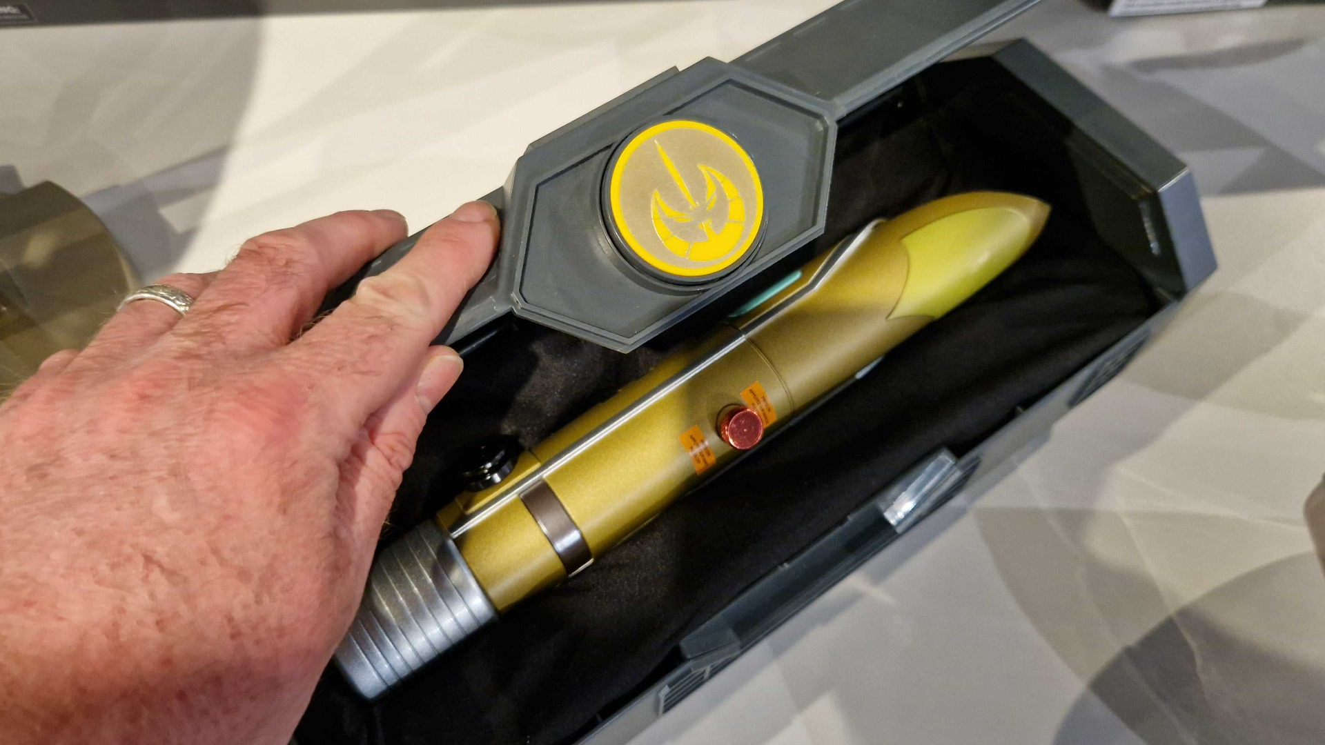 A hand opens a Star Wars lightsaber case