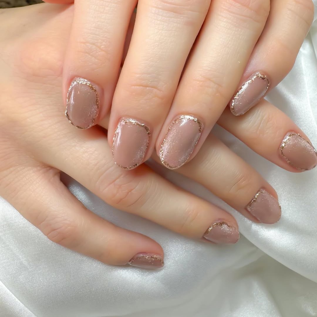 A shimmery cateye nude manicure trimmed with gold foil.