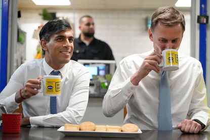 UK prime minister Rishi Sunak (left) and chancellor Jeremy Hunt have a drink and biscuits during a visit to a building warehouse on 6 March 2024 in London, England. 