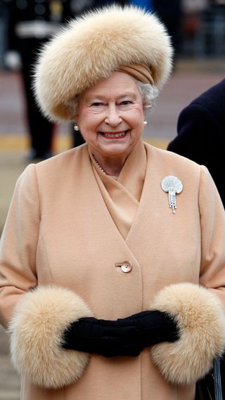 Queen Elizabeth in a fluffy hat at the unveiling of a statue for the Queen Mother