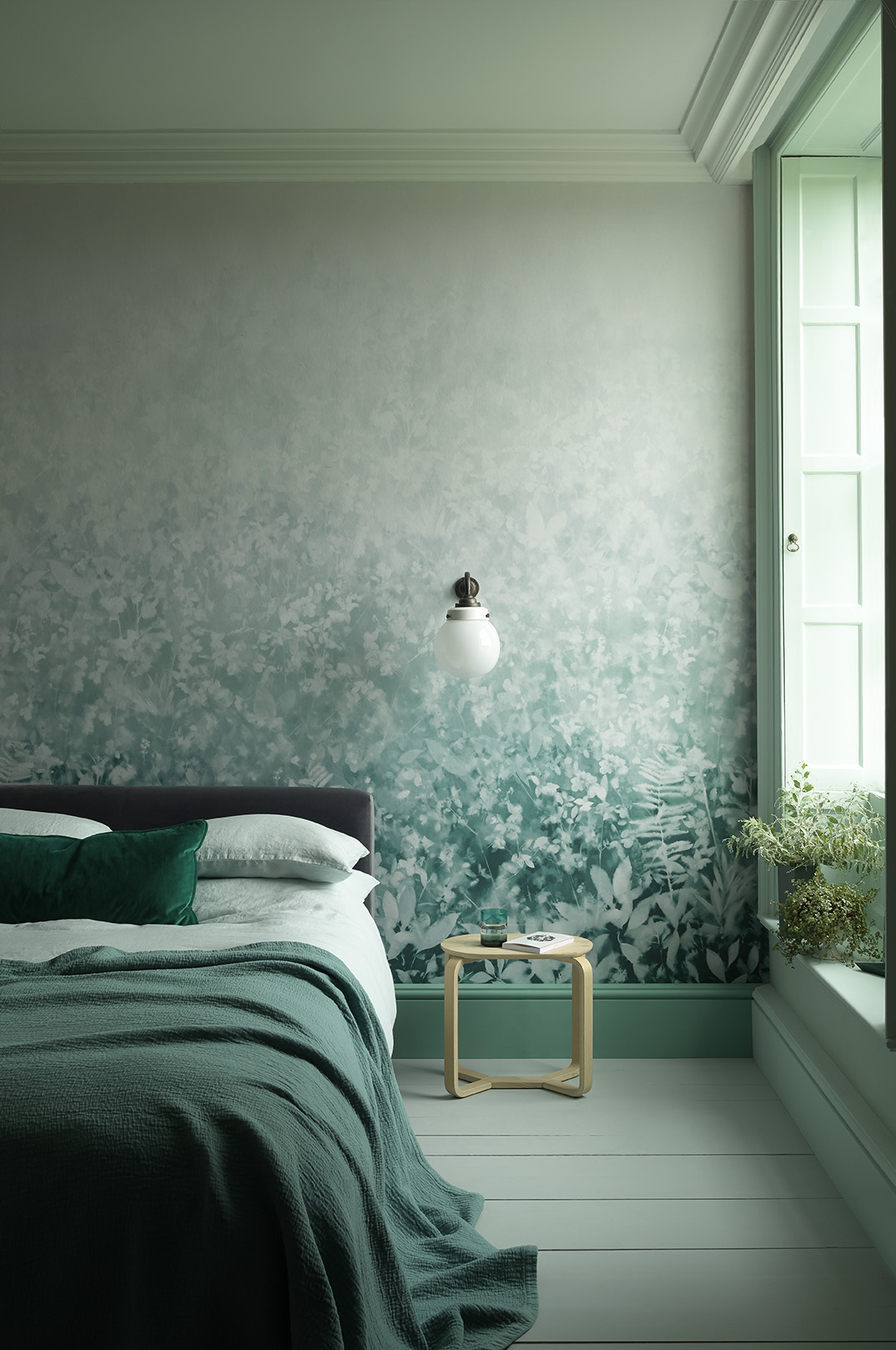 A pale sea-green scheme with cohesive colors, a leaf-print wallpaper and teal throw illustrating how to choose the best bedroom colors.