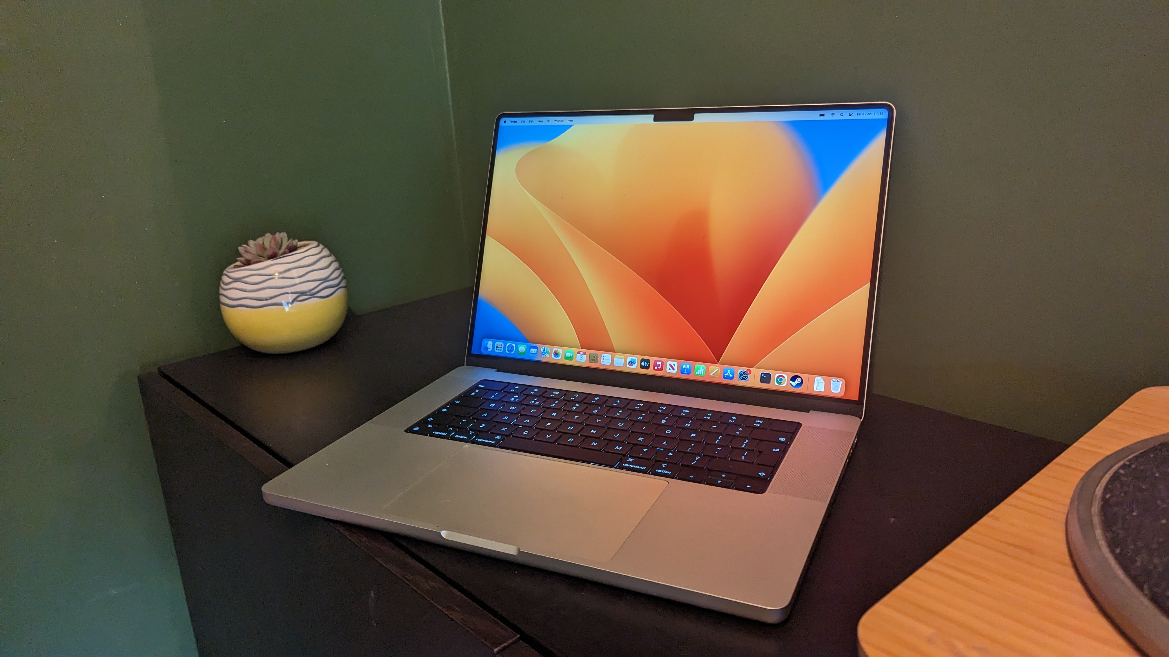 MacBook Pro 16 дюймов (2023 г.) на деревянном столе с зеленым фоном