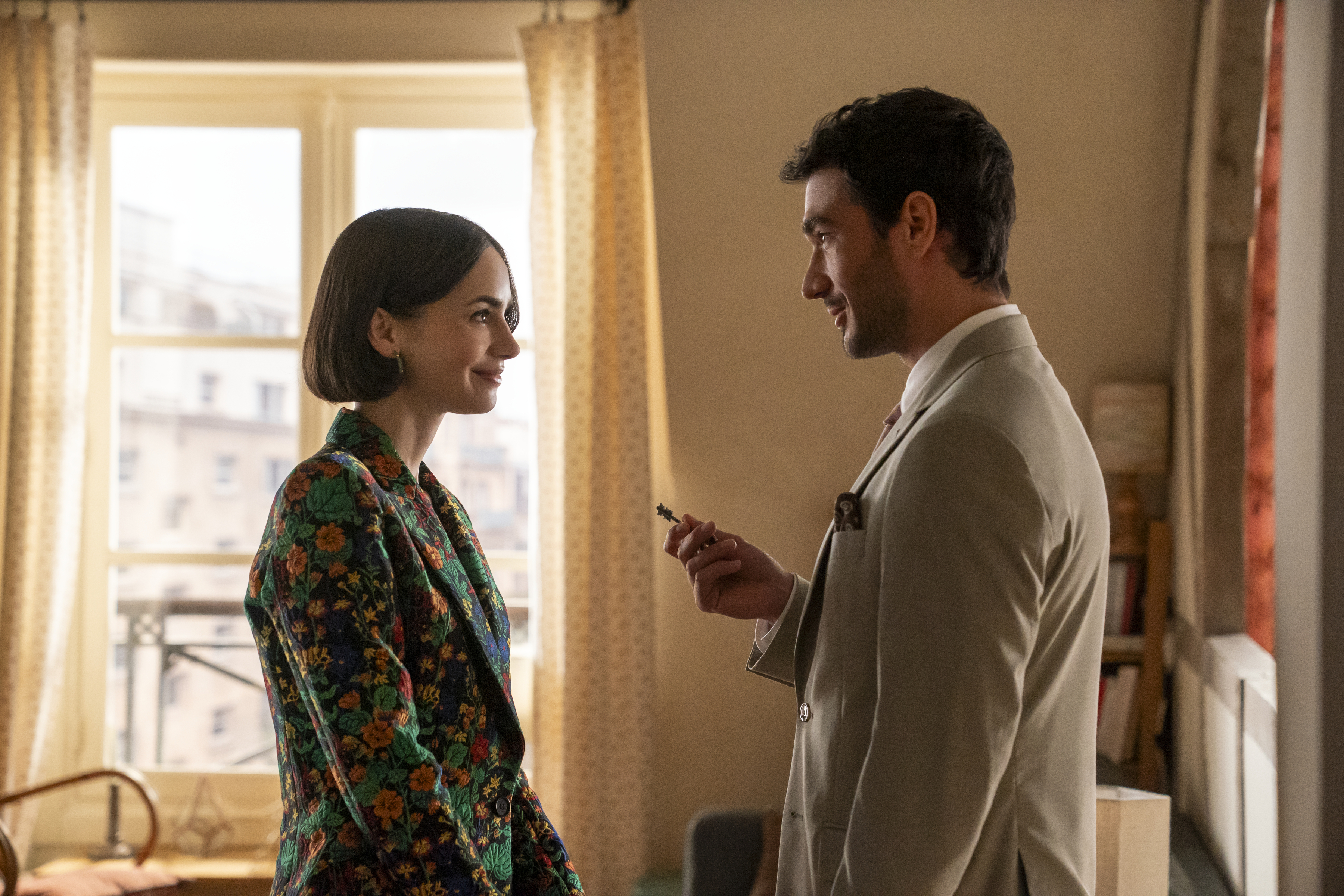 Two people (Lily Collins as Emily, Eugenio Franceschini as Marcello) stand in a Paris apartment as the man holds a key, in episode 508 of 'Emily In Paris.'