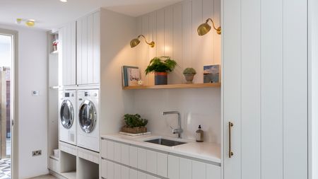 A utility room with sink, cabinetry, and washing machines