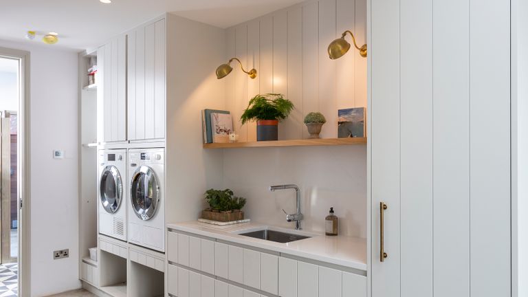A utility room with sink, cabinetry, and washing machines