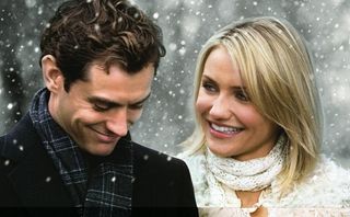 Cameron Diaz står bredvid Jude Law utomhus när det snöar och kollar glatt och kärleksfullt på honom.