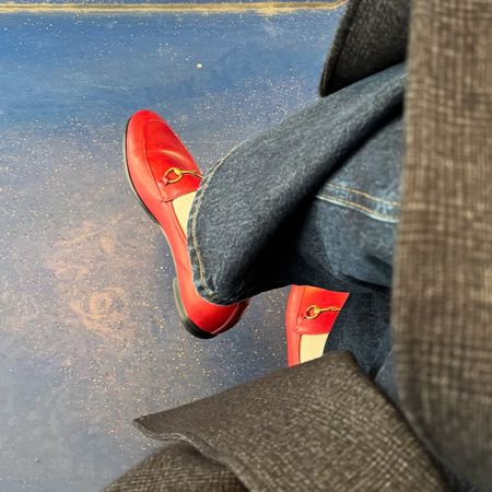 Photo of red Gucci loafers with butter yellow socks, dark straight jeans and a Tibi coat.