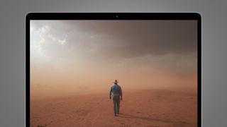 A man walking into a dust storm on a MacBook screen