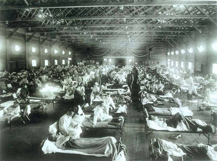 black and white photo of a hospital ward with four long rows of beds stretching away from the camera
