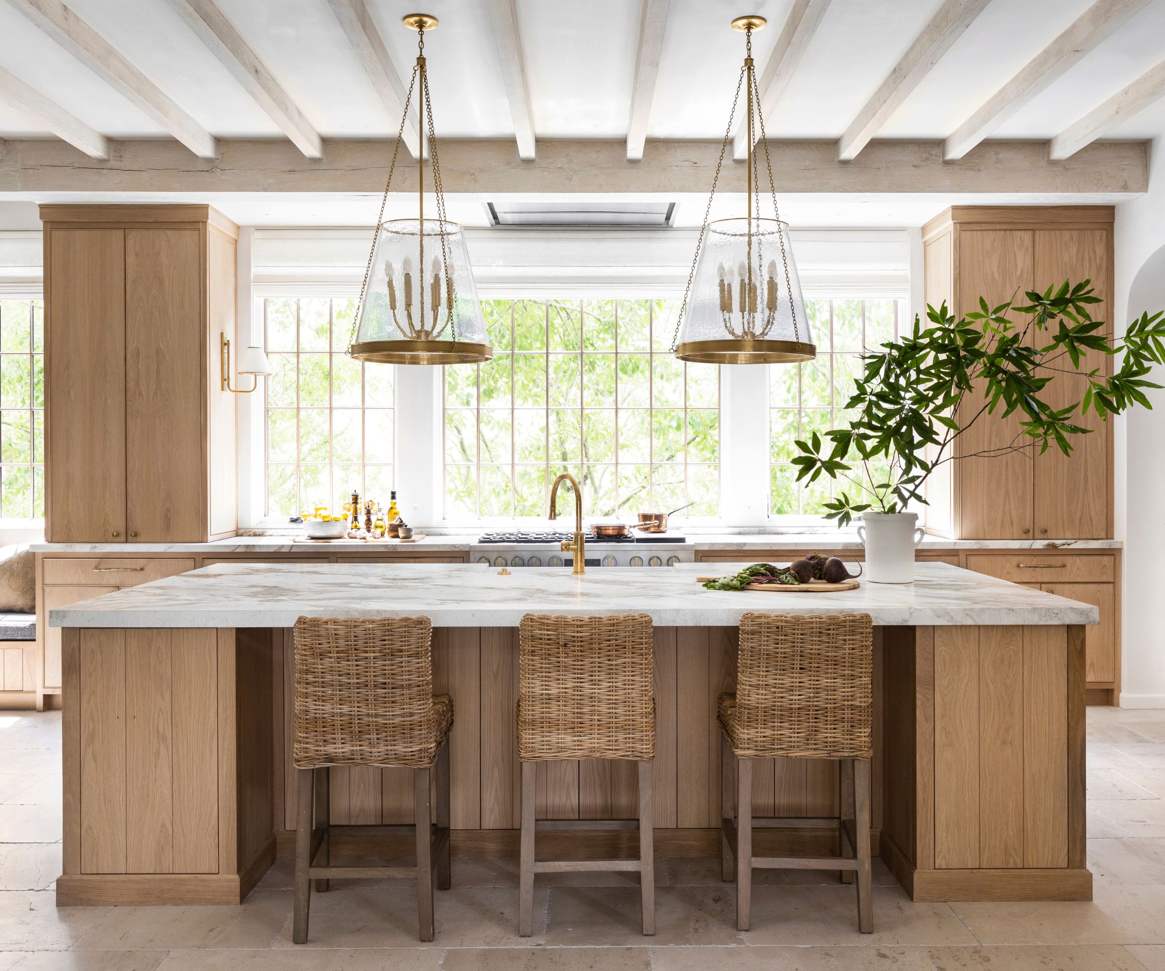 A white oak kitchen with marble countertops and brass accents