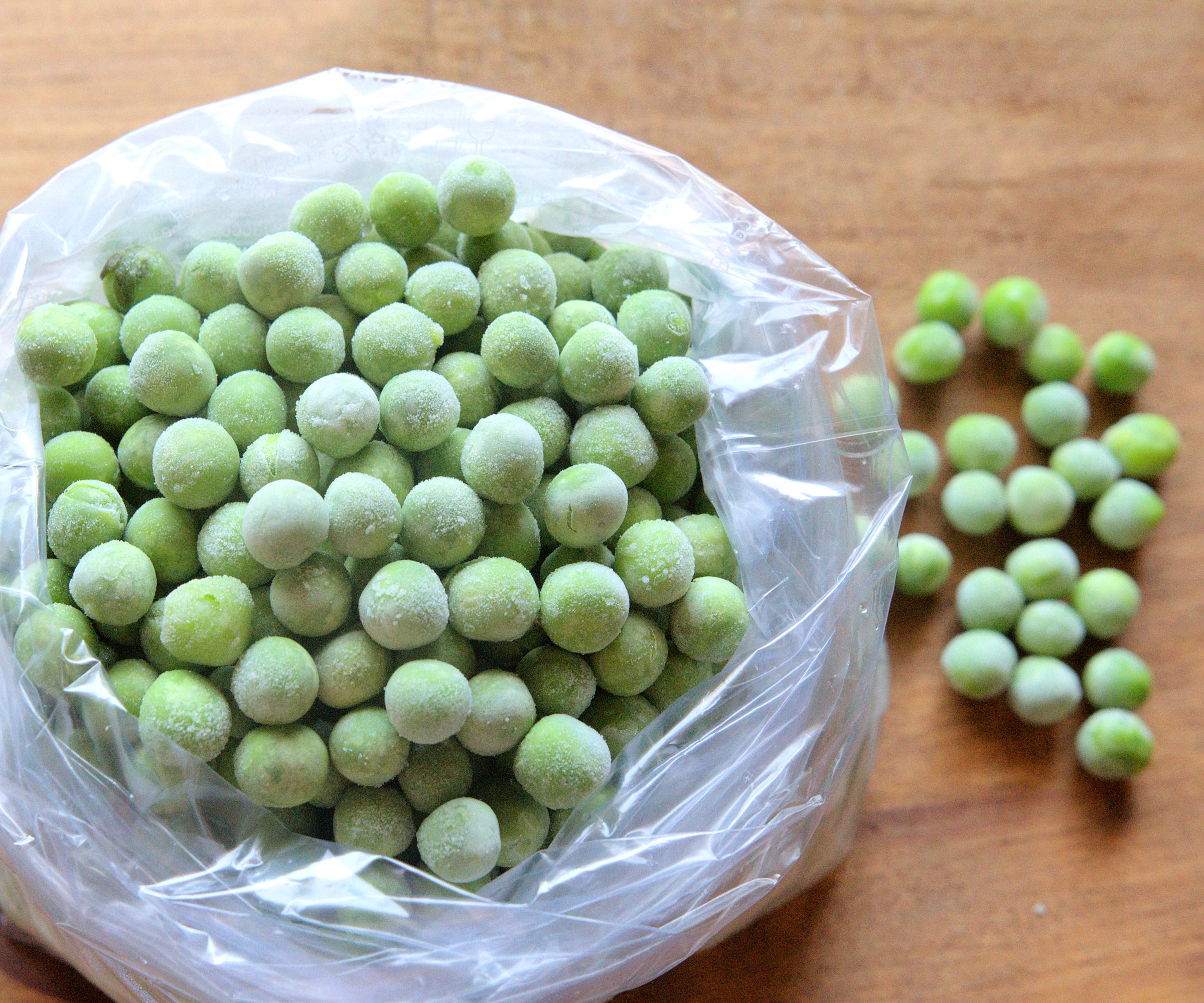 frozen peas in a plastic bag on wooden kitchen table