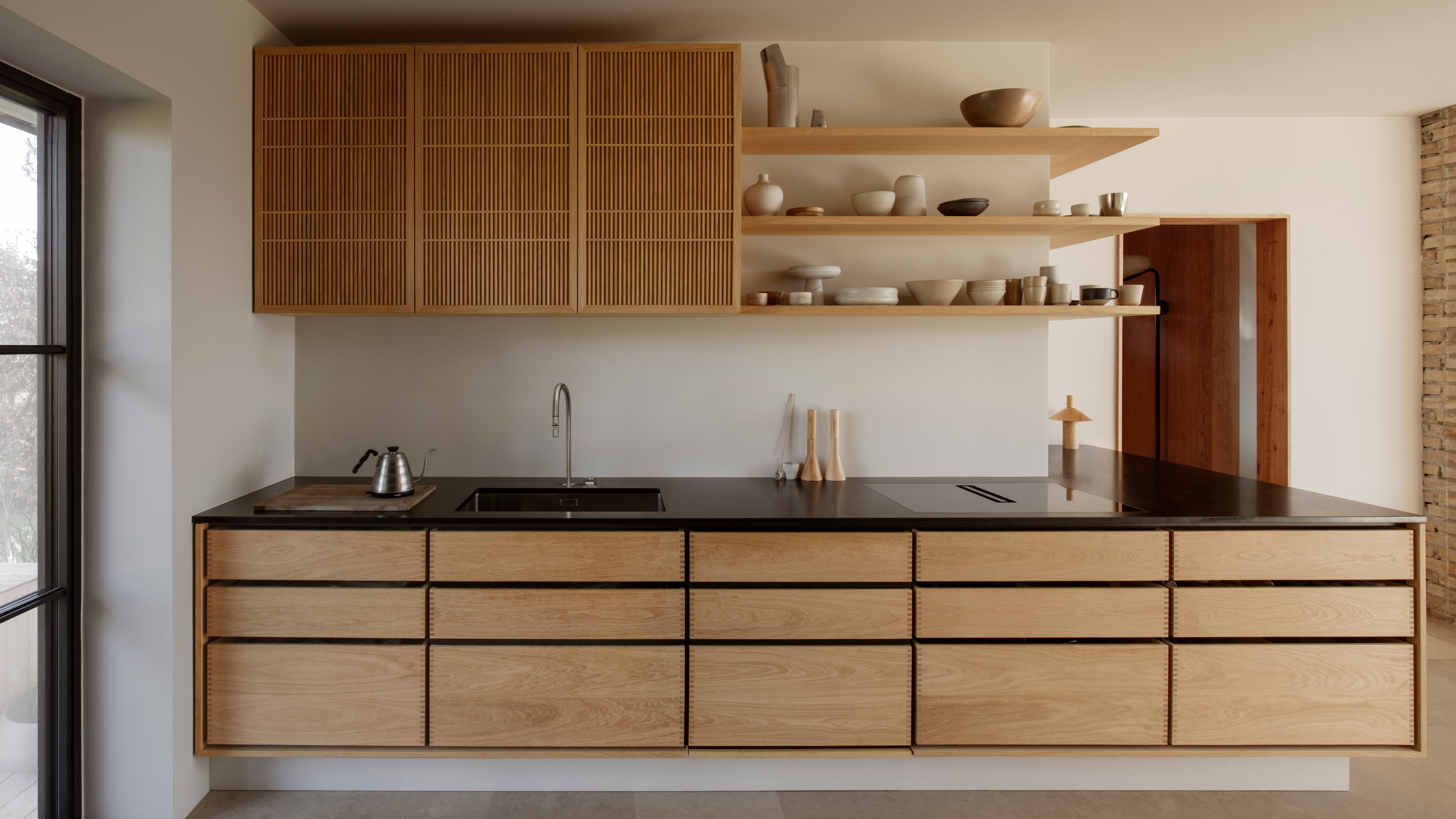 wooden scandi kitchen with black counters and open shelving above