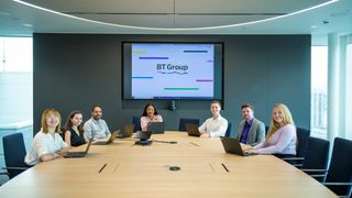 Seven young adults from the BT Group apprenticeship program sitting round a board table