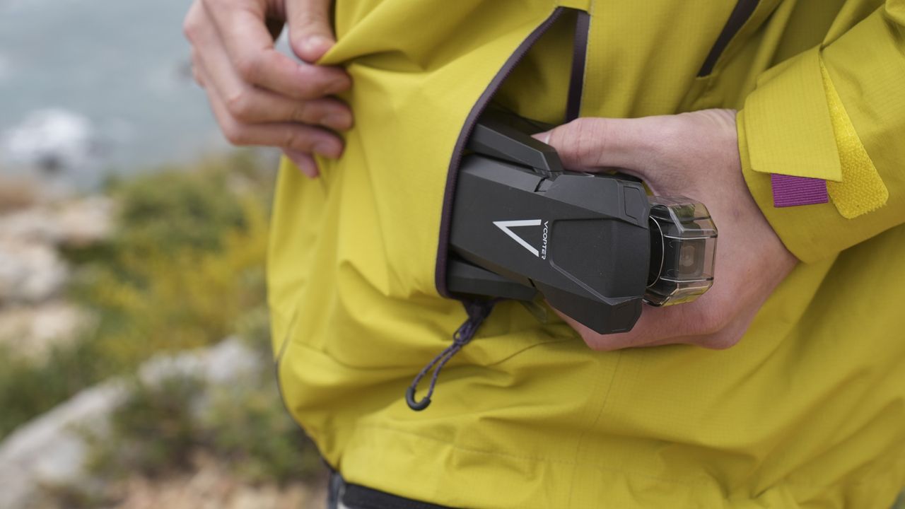 V-Copter Falcon Mini drone being placed into a jacket pocket