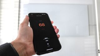 A person using the Boldr app to control the Boldr Kelvin wall-mounted, smart infrared heater