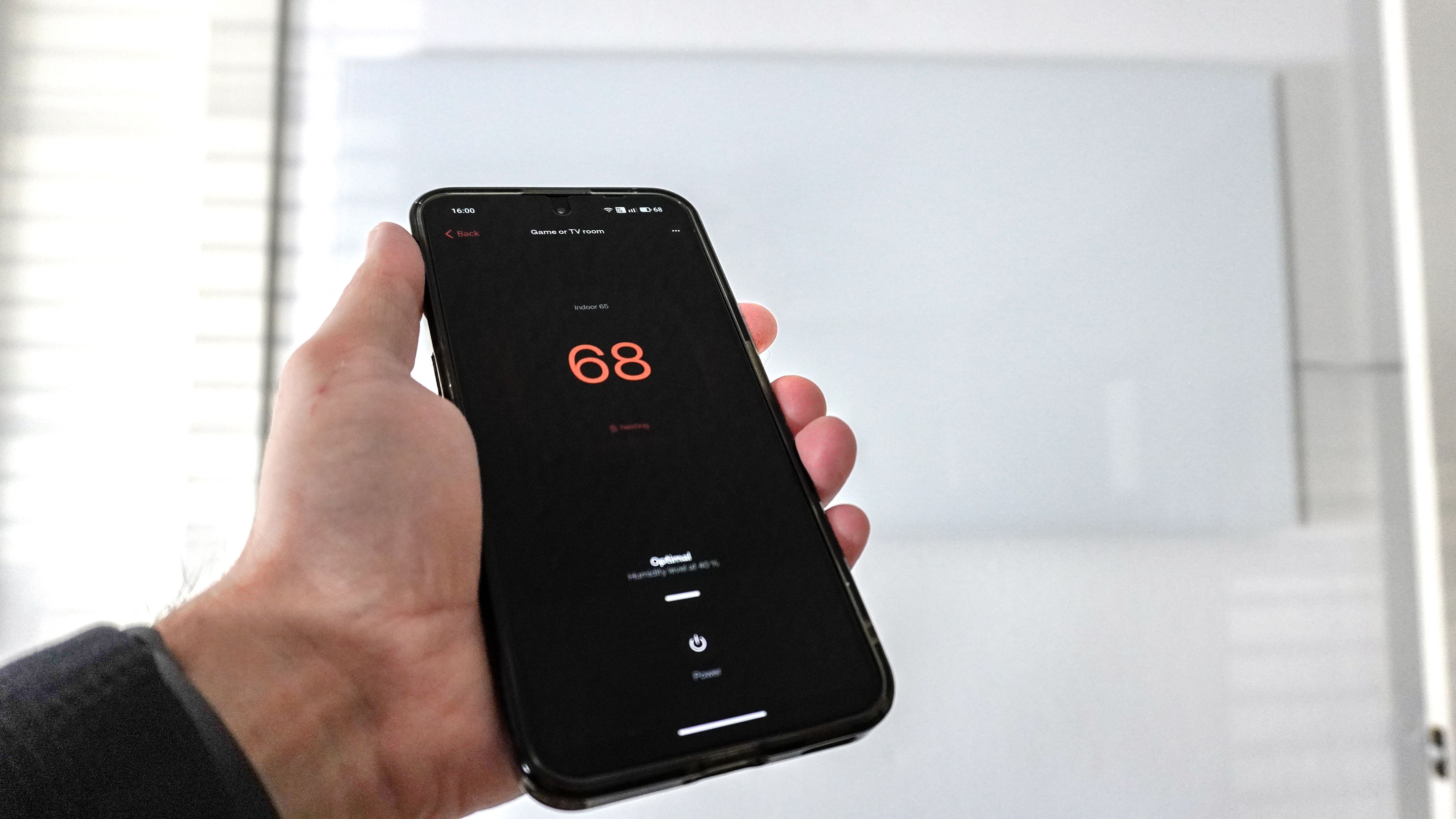 A person using the Boldr app to control the Boldr Kelvin wall-mounted, smart infrared heater