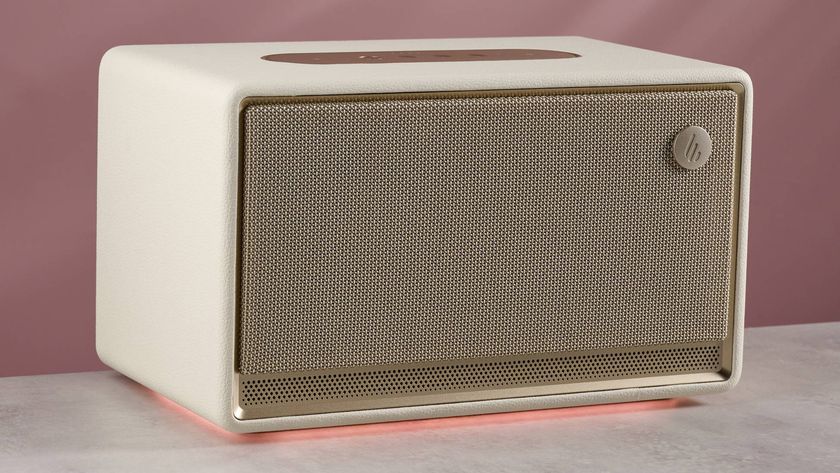 The Edifier ES300 with a glowing amber light beneath, in front of a pink background.