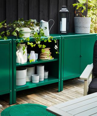 green metal storage unit against a black timber wall on a balcony