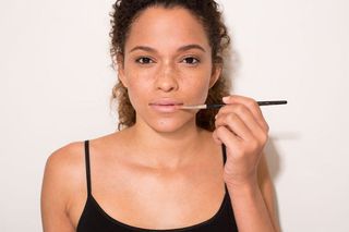 Model applying concealer on Lips