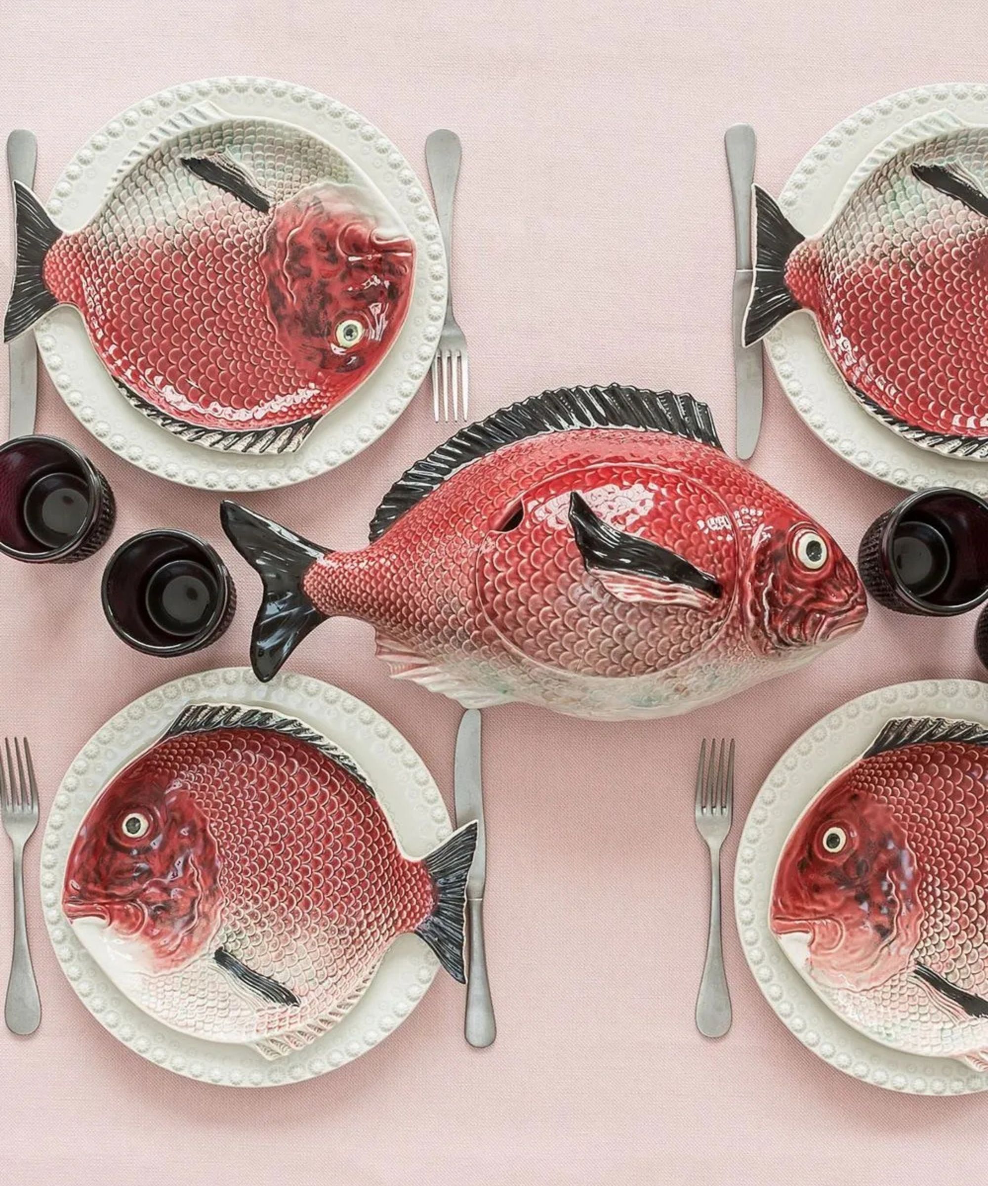 Bordallo Pinheiro fish plates on table with silver cutlery, white plates, and pink tablecloth