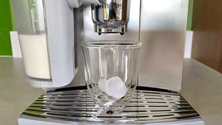 Philips Cafe Aromis Series 8000 coffee maker ready to dispense coffee into glass cup containing ice