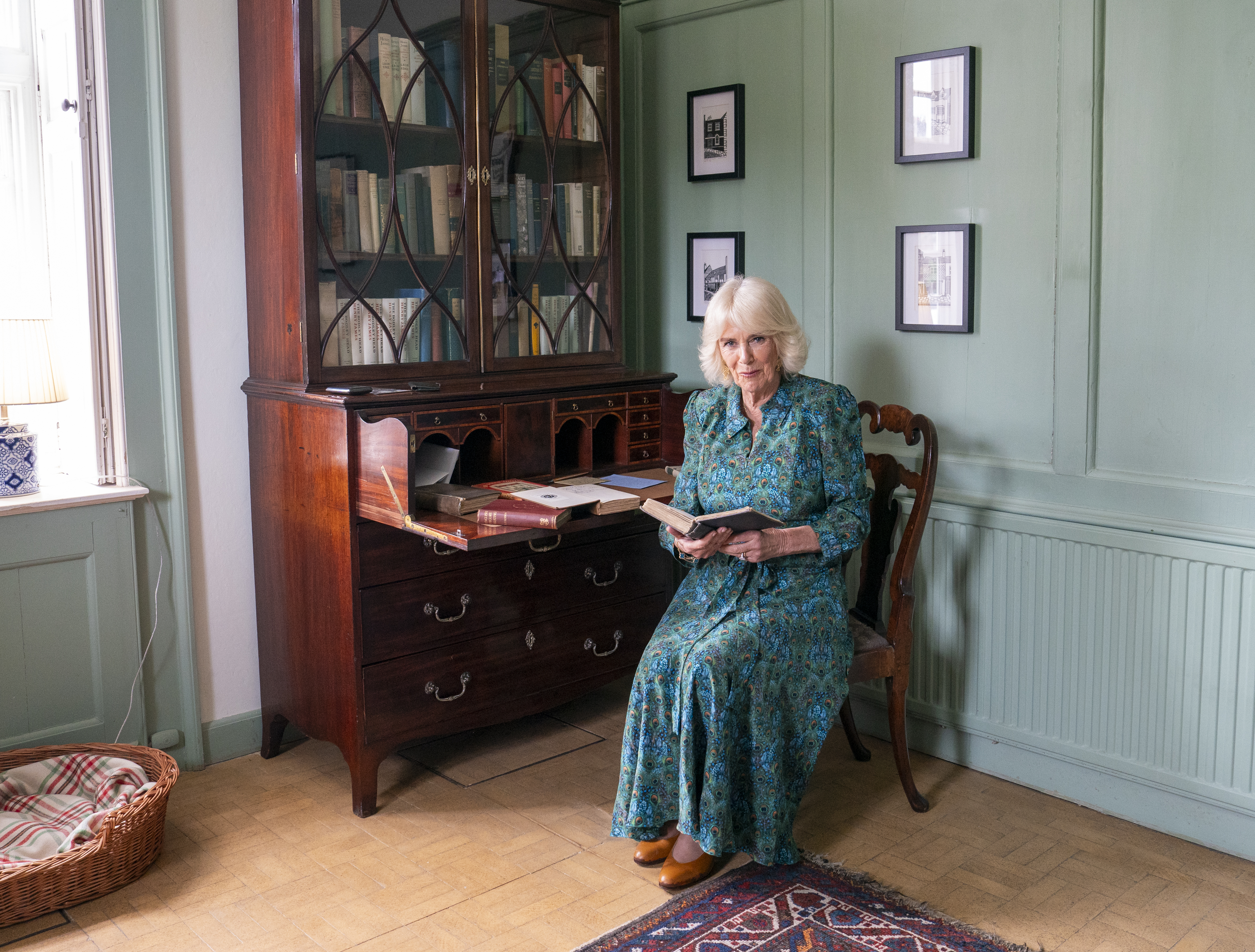 Queen Camilla sitting at a desk reading books.