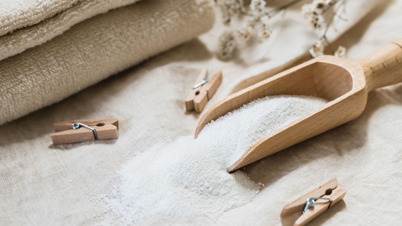 A wooden scoop with laundry detergent and wooden pegs