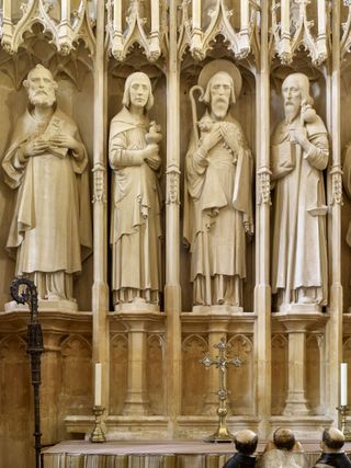 Winchester Cathedral: The reredos of Bishop Wykeham’s chantry. Its sculpture of 1897 by Sir George Frampton is being admired by three tiny praying figures, restored to resemble monks, on the Bishop’s tomb below.