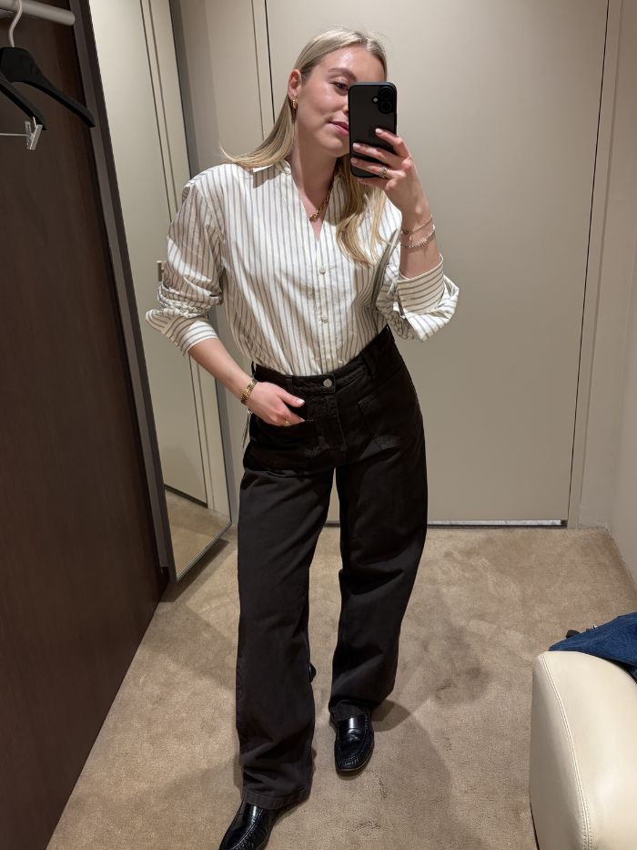 Woman wears striped shirt, brown jeans and black loafers