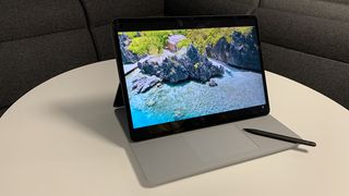 A Microsoft Surface Studio Laptop sitting on a desk with a stylus next to it.