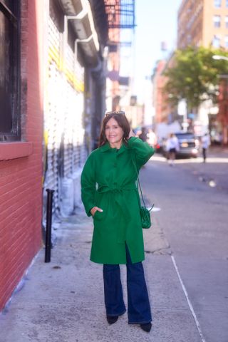 A former Nordstrom buyer wearing a green longline coat over bootcut jeans.