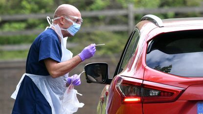An NHS nurse carries out a Covid test at a drive-through testing centre.