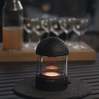 lantern style light on a table at dusk in front of a tray with glasses on it